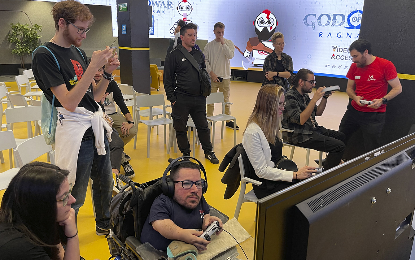 Varias personas jugando a God of War Ragnarok, entre ellas, Moyorz87, persona con discapacidad física, junto a otras personas sin discapacidad de ningún tipo, probando el juego como si tuvieran algún tipo de discapacidad.